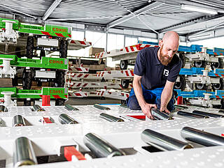 Man installs the carrying rollers on a dolly