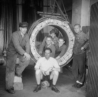 Bernhard Blumenbecker and his former colleagues standing in front of a motor.