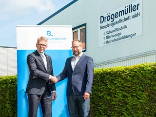 Managing directors shake hands in front of the Drögemüller building