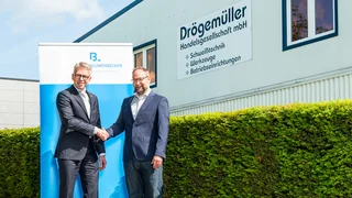 Managing directors shake hands in front of the Drögemüller building